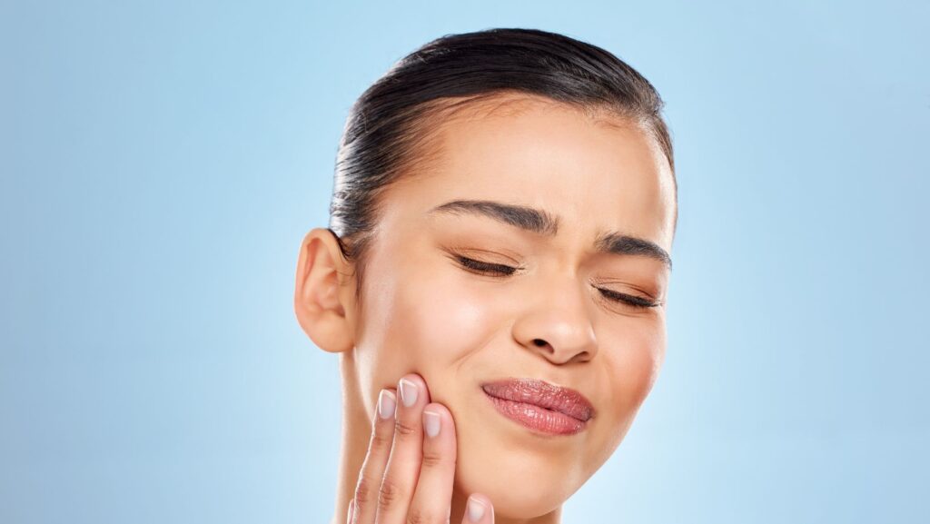 A woman touching her jaw in discomfort, illustrating TMJ pain, often treated with Botox.